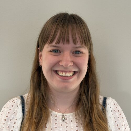 En leende kvinna med ljusbrunt hår och lugg.