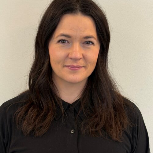 En leende mörkhårig kvinna klädd i en svart skjorta.